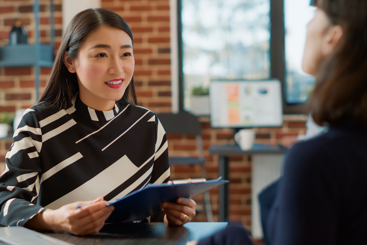 Two young women at desk conversing