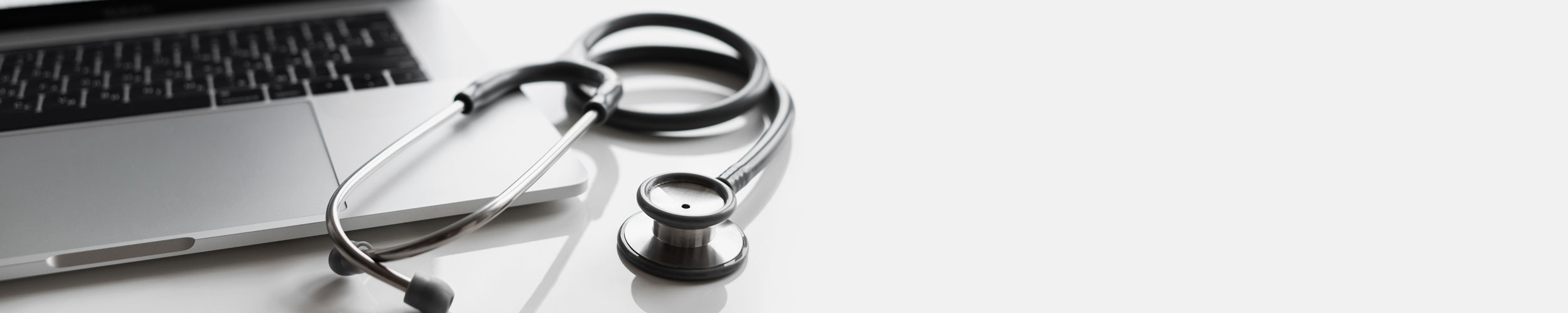 black & white close up of stethoscope and computer keyboard