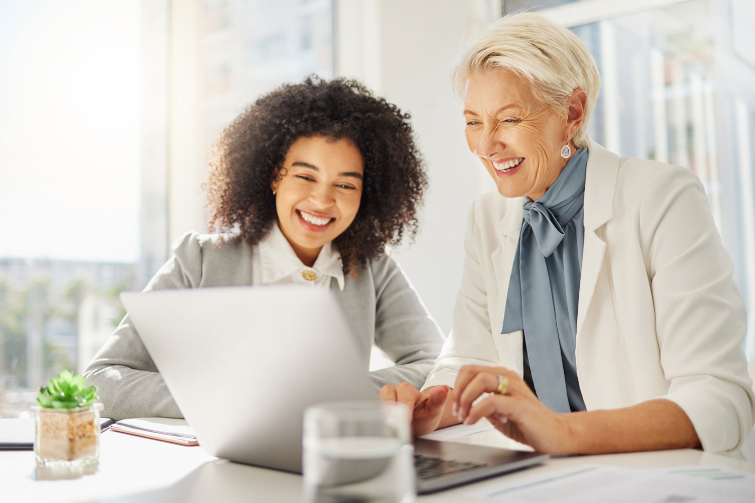 mature woman advising young professional with laptop