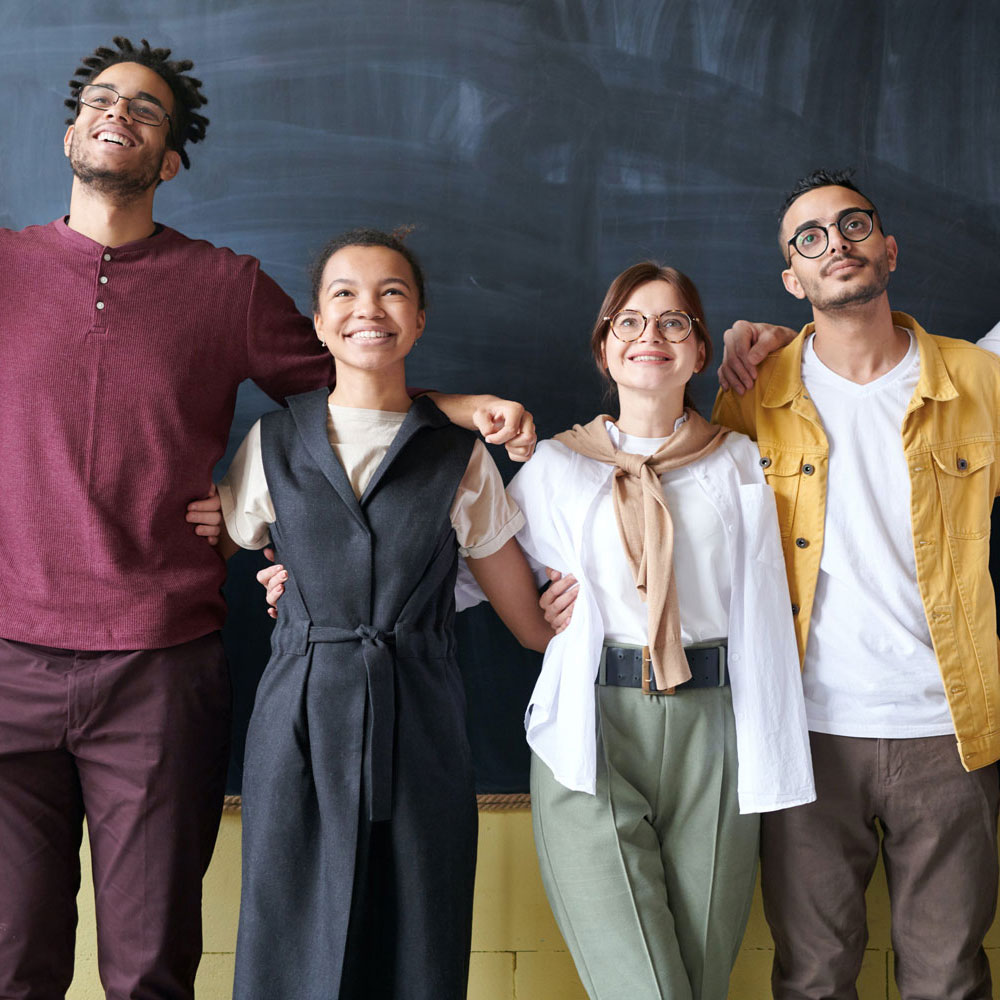 Group of smiling individuals in front of blackboard