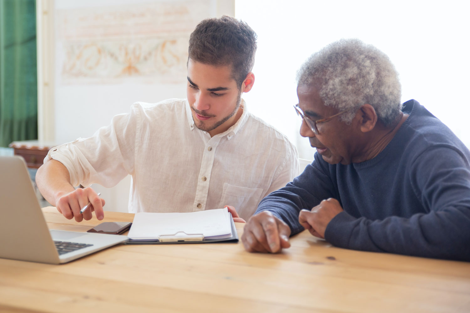 young man helping older man with laptop