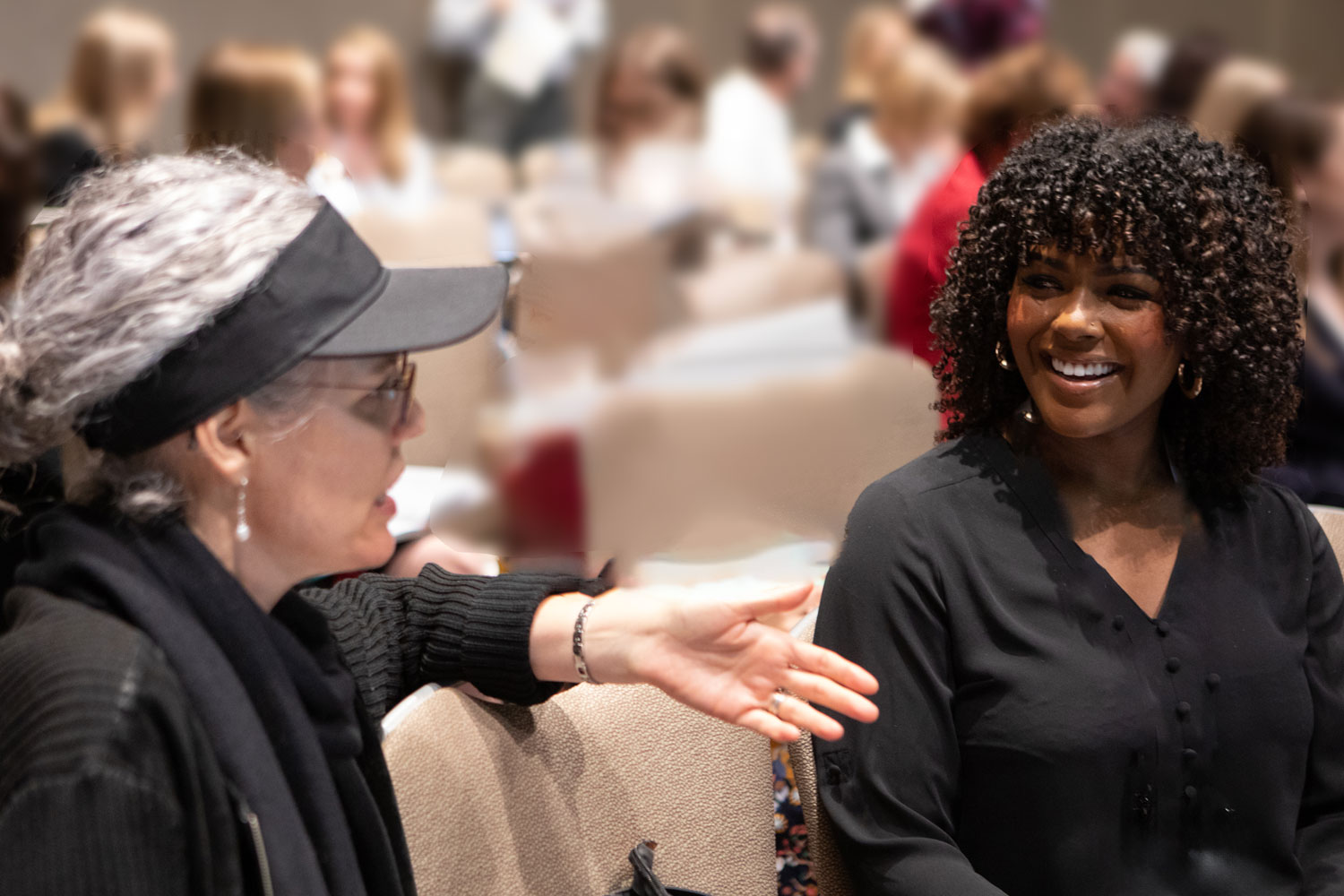 two women conversing in conference setting