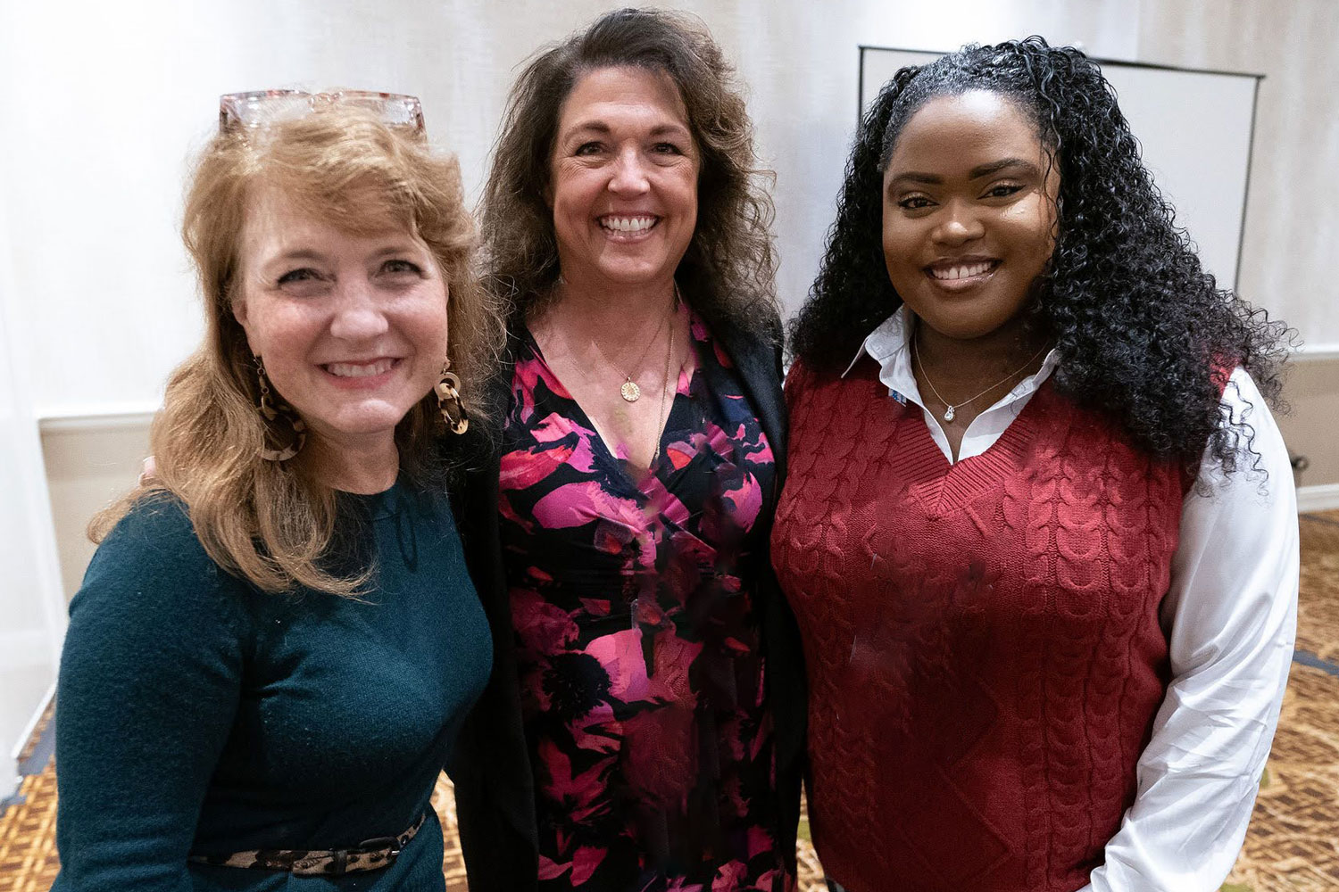 three smiling professional woman of various ages